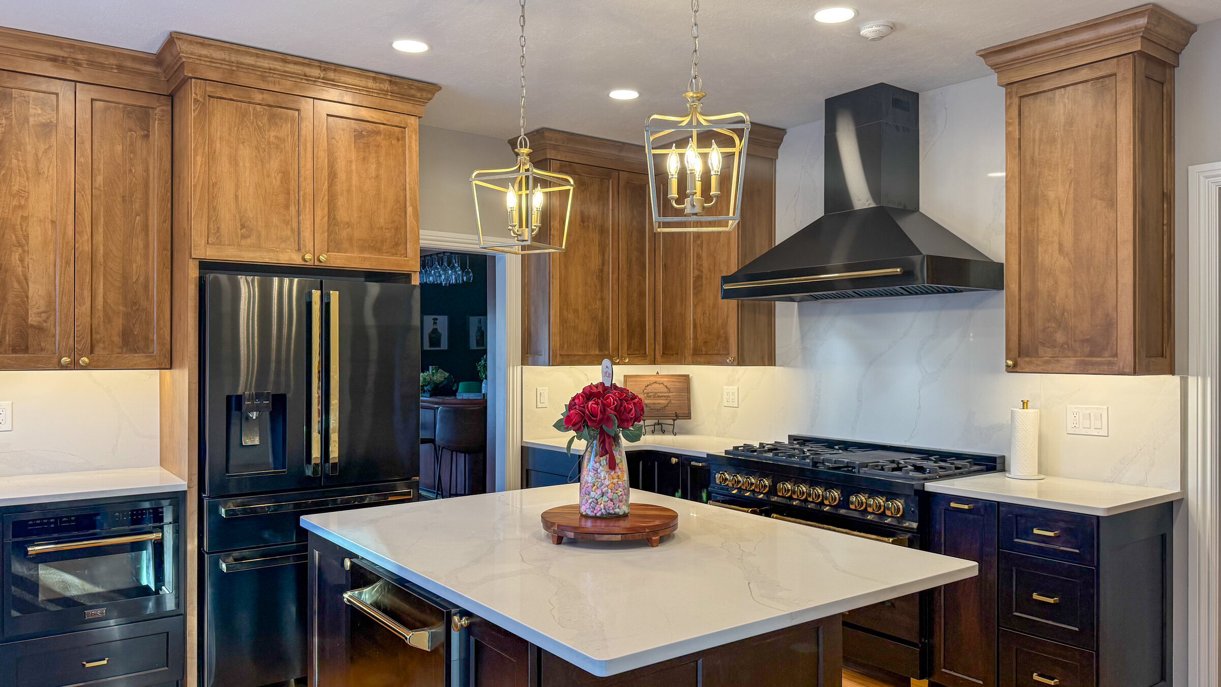 Kitchen remodel with stained wood cabinetry, black stainless appliances, and black range hood with brass accents - Marcus Sebastian Renovations